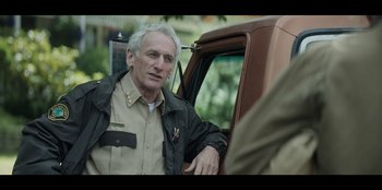 Movie still from “Lou” (2022), directed by Anna Foerster – An older man sitting in the drivers seat of a truck; Close Up shot, Over the shoulder angle