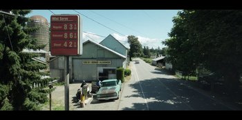 Movie still from “Lou” (2022), directed by Anna Foerster – A man standing on the side of a road next to a car; Extreme Wide shot, High angle