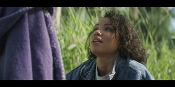 Movie still from “Lou” (2022), directed by Anna Foerster – A woman with curly hair is looking up at the sky; Close Up shot, Over the shoulder angle