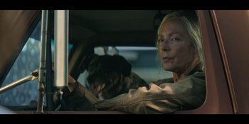 Movie still from “Lou” (2022), directed by Anna Foerster – A woman driving a car with a dog sitting in the passenger seat; Close Up shot, Over the shoulder angle