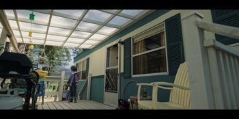 Movie still from “Lou” (2022), directed by Anna Foerster – A little girl standing on the porch of a house; Wide shot, Low angle