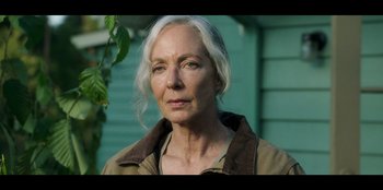 Movie still from “Lou” (2022), directed by Anna Foerster – An older woman with white hair is standing in front of a building; Close Up shot, Low angle