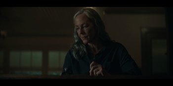 Movie still from “Lou” (2022), directed by Anna Foerster – An older woman in a black shirt is looking at a cell phone; Close Up shot, Over the shoulder angle