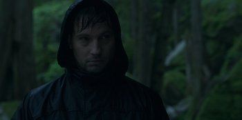 Movie still from “Lou” (2022), directed by Anna Foerster – A man wearing a black jacket in the woods; Close Up shot, Low angle