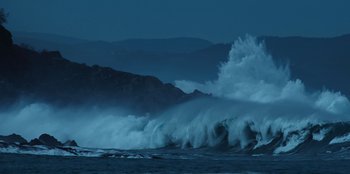 Movie still from “Lou” (2022), directed by Anna Foerster – A large wave crashing on the shore of a body of water at night; Extreme Wide shot, Low angle