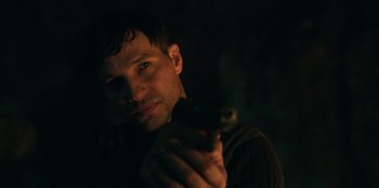 Movie still from “Lou” (2022), directed by Anna Foerster – A man holding a gun in his hand; Close Up shot, Over the shoulder angle
