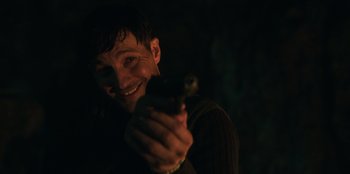 Movie still from “Lou” (2022), directed by Anna Foerster – A man holding a gun in a dark room; Close Up shot, Over the shoulder angle