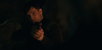 Movie still from “Lou” (2022), directed by Anna Foerster – A man is holding a gun in the dark; Close Up shot, Over the shoulder angle