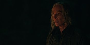 Movie still from “Lou” (2022), directed by Anna Foerster – A woman with long blonde hair is standing in the dark; Close Up shot, Over the shoulder angle