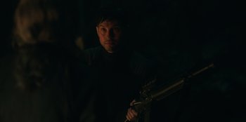 Movie still from “Lou” (2022), directed by Anna Foerster – A man in a dark room holding a gun; Close Up shot, Over the shoulder angle