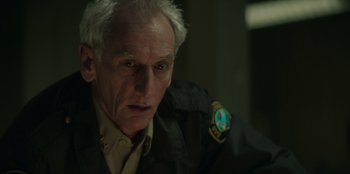 Movie still from “Lou” (2022), directed by Anna Foerster – An older man in a uniform looking at the camera; Close Up shot, Low angle