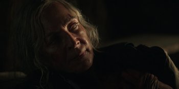 Movie still from “Lou” (2022), directed by Anna Foerster – An older woman with blonde curly hair looking at the camera; Close Up shot, Over the shoulder angle