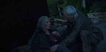 Movie still from “Lou” (2022), directed by Anna Foerster – An older man and a younger woman sitting on the ground; Medium shot, High angle