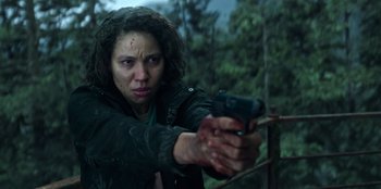 Movie still from “Lou” (2022), directed by Anna Foerster – A woman is holding a gun in the woods; Close Up shot, Low angle