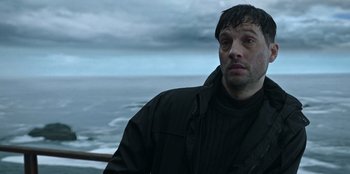 Movie still from “Lou” (2022), directed by Anna Foerster – A person wearing a jacket near a body of water; Close Up shot, Low angle