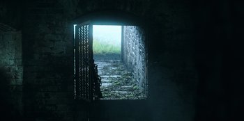 Movie still from “Lou” (2022), directed by Anna Foerster – A door leading to a room with a brick wall; Extreme Wide shot, Low angle
