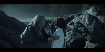 Movie still from “Lou” (2022), directed by Anna Foerster – A man and a child are standing next to rocks; Medium shot, Over the shoulder angle