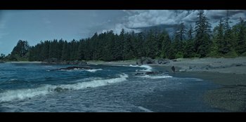 Movie still from “Lou” (2022), directed by Anna Foerster – A person standing on a beach near the ocean; Extreme Wide shot, High angle