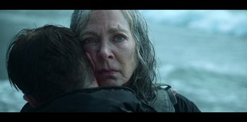 Movie still from “Lou” (2022), directed by Anna Foerster – An older woman holding a young man in her arms; Close Up shot, Over the shoulder angle