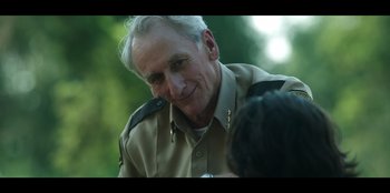 Movie still from “Lou” (2022), directed by Anna Foerster – An older man in a tan shirt is talking to someone; Close Up shot, Over the shoulder angle