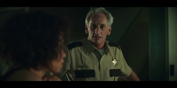 Movie still from “Lou” (2022), directed by Anna Foerster – A man in a police uniform talking to a woman; Close Up shot, Low angle