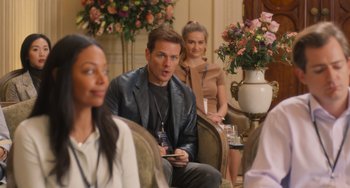 Movie still from “Love Again” (2023), directed by Jim Strouse – A group of people sitting in a living room; Medium shot, Over the shoulder angle