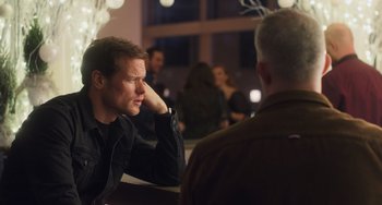 Movie still from “Love Again” (2023), directed by Jim Strouse – A man sitting in front of another man at a table; Close Up shot, Over the shoulder angle