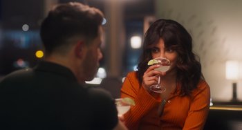 Movie still from “Love Again” (2023), directed by Jim Strouse – A man and a woman sitting in front of each other holding drinks; Close Up shot, Over the shoulder angle