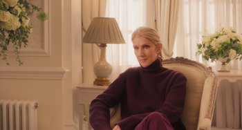 Movie still from “Love Again” (2023), directed by Jim Strouse – A woman sitting in a chair in front of a lamp; Medium shot, Low angle
