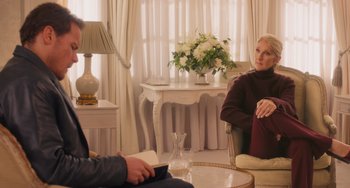 Movie still from “Love Again” (2023), directed by Jim Strouse – Two people are sitting in a living room; Medium shot, Over the shoulder angle