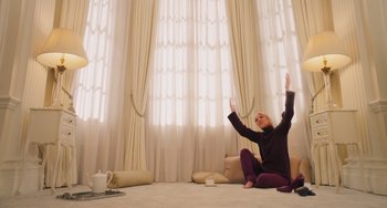 Movie still from “Love Again” (2023), directed by Jim Strouse – A woman sitting on the ground with her arms in the air; Wide shot, Low angle