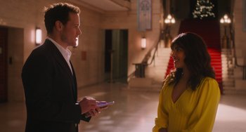 Movie still from “Love Again” (2023), directed by Jim Strouse – A man and a woman are talking in a hallway; Medium shot, Over the shoulder angle