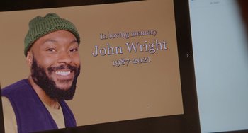 Movie still from “Love Again” (2023), directed by Jim Strouse – A plaque with a picture of a man with a beard; Extreme Close Up shot, High angle