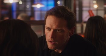 Movie still from “Love Again” (2023), directed by Jim Strouse – A person sitting at a table; Close Up shot, Over the shoulder angle