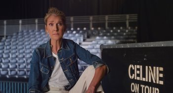 Movie still from “Love Again” (2023), directed by Jim Strouse – A woman sitting on a bench in a stadium; Medium shot, Low angle