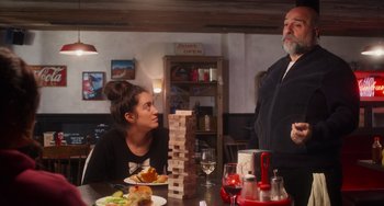 Movie still from “Love Again” (2023), directed by Jim Strouse – A man and a woman sitting at a table; Medium shot, Over the shoulder angle