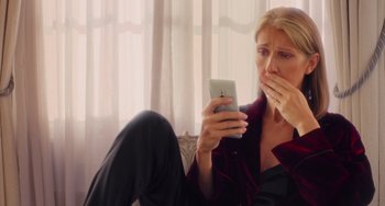 Movie still from “Love Again” (2023), directed by Jim Strouse – A woman sitting on the ground looking at a cell phone; Close Up shot, Low angle