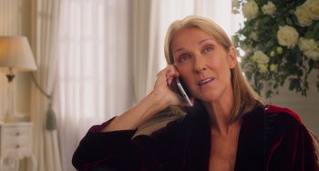 Movie still from “Love Again” (2023), directed by Jim Strouse – A woman talking on a cell phone while sitting in a chair; Close Up shot, Overhead angle