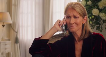 Movie still from “Love Again” (2023), directed by Jim Strouse – A woman sitting on a chair talking on a cell phone; Close Up shot, High angle