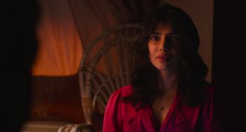 Movie still from “Love Again” (2023), directed by Jim Strouse – A woman in a pink shirt is standing in front of a wicker chair; Close Up shot, High angle