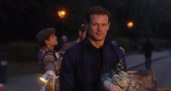 Movie still from “Love Again” (2023), directed by Jim Strouse – A man holding a bouquet of flowers in his hand; Medium shot, Over the shoulder angle