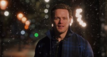 Movie still from “Love Again” (2023), directed by Jim Strouse – A man in a plaid jacket standing in the snow; Close Up shot, Over the shoulder angle