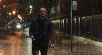 Movie still from “Love Again” (2023), directed by Jim Strouse – A man walking down a street in the rain; Medium shot, Low angle