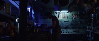 Movie still from “Love and Monsters” (2020), directed by Michael Matthews – A man working in an electrical shop at night; Medium shot, Low angle