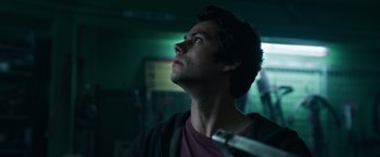 Movie still from “Love and Monsters” (2020), directed by Michael Matthews – A man looking up into the sky in a dark room; Close Up shot, Low angle