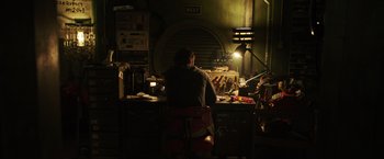 Movie still from “Love and Monsters” (2020), directed by Michael Matthews – A man sitting at a desk in a dark room; Wide shot, High angle