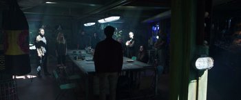 Movie still from “Love and Monsters” (2020), directed by Michael Matthews – A group of people sitting around a table; Wide shot, Over the shoulder angle