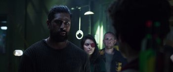 Movie still from “Love and Monsters” (2020), directed by Michael Matthews – A group of people standing in a dark room; Medium shot, Over the shoulder angle