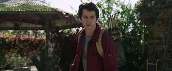 Movie still from “Love and Monsters” (2020), directed by Michael Matthews – A young man with a backpack holding a bunch of arrows; Close Up shot, Over the shoulder angle