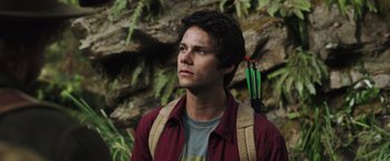 Movie still from “Love and Monsters” (2020), directed by Michael Matthews – A young man holding a bow and arrow in a forest; Close Up shot, Low angle